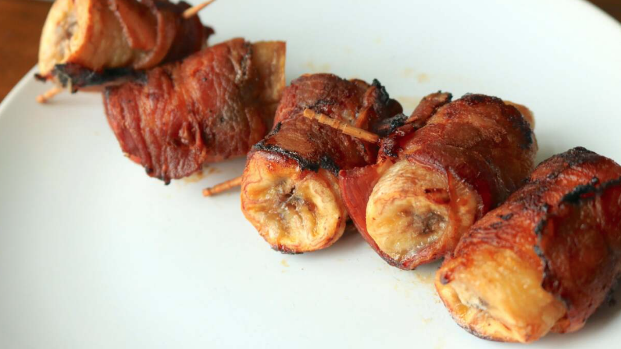 Bacon-wrapped banana bites on a plate.