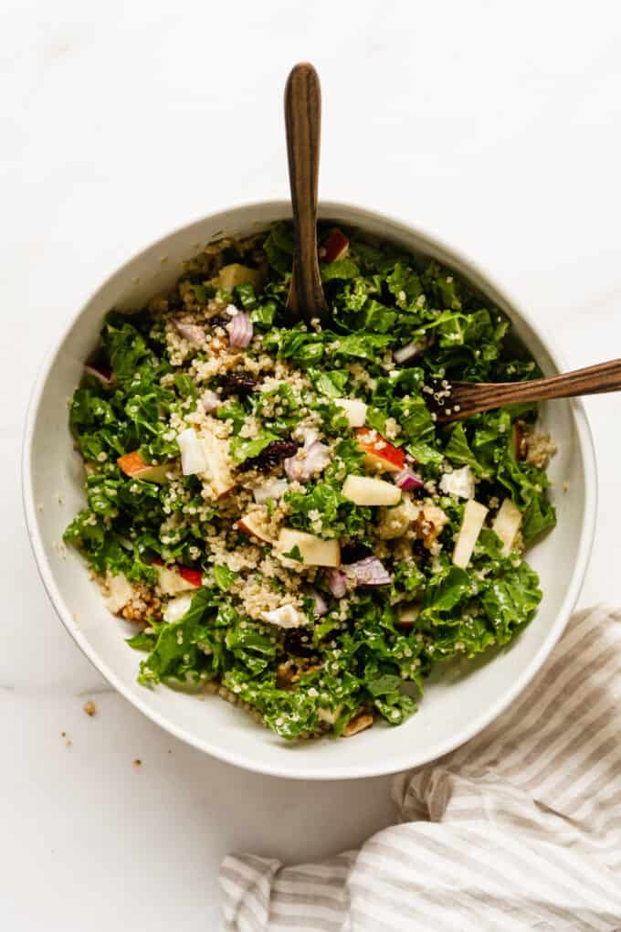 apple quinoa salad in a bowl with two wood spoons