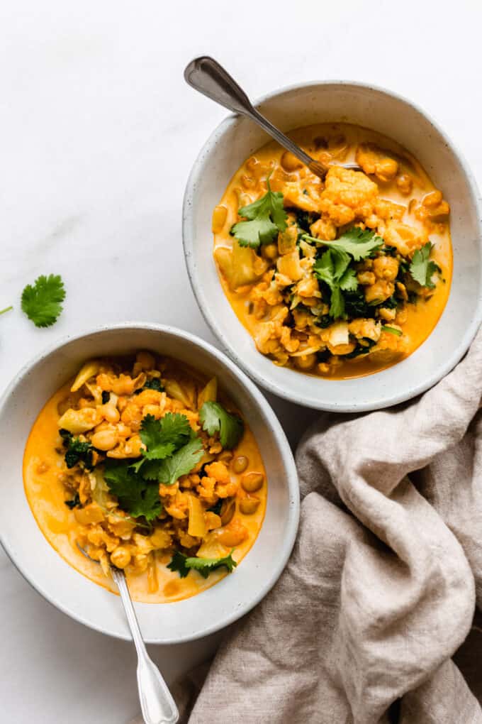 two bowls of coconut cauliflower curry topped with cilantro