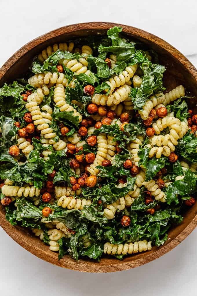 a kale caesar pasta salad in a wood mixing bowl