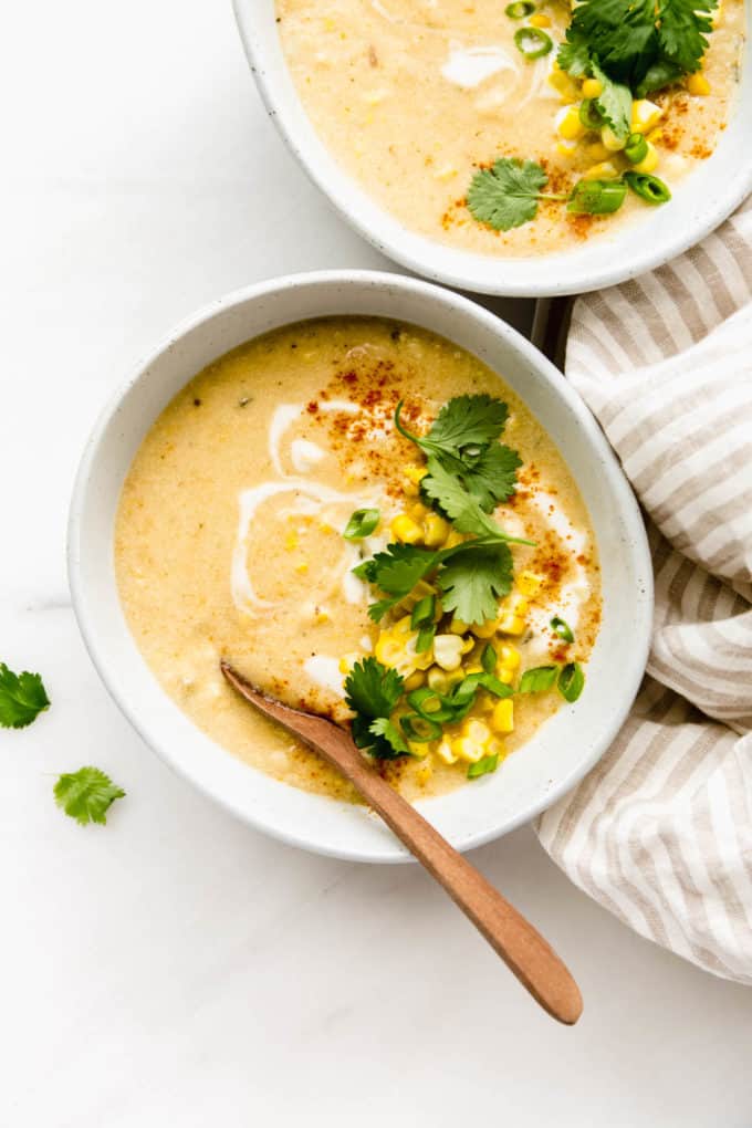 A bowl of vegan corn chowder with a wood spoon in it